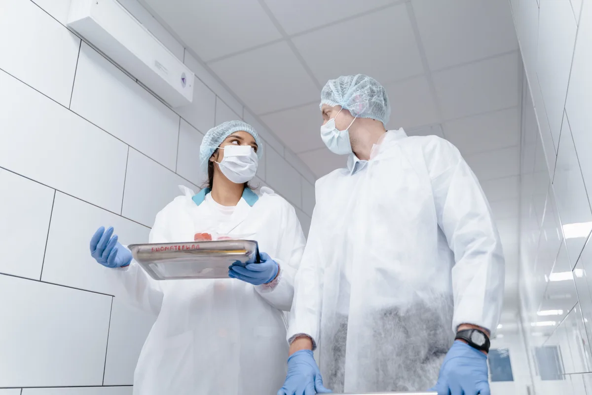 Laboratórni pracovníci v ochrannom odeve pri manipulácii so vzorkami